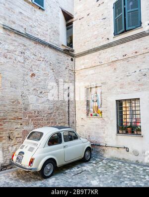 Ein berühmter Wagen des Fiats 500, der in den Straßen der mittelalterlichen Stadt Foligno, Italien, geparkt ist und über ihm ein Gemälde der Madonna angebracht ist. Stockfoto