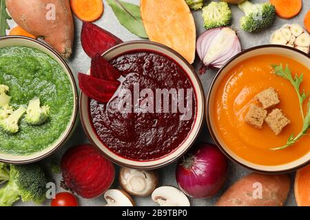 Gemüsesuppen und Zutaten auf grauem Hintergrund, Draufsicht Stockfoto