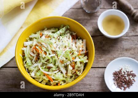 Krautsalat von Kohl, Karotten und verschiedenen Kräutern mit Mayonnaise in einer großen Platte auf einem hölzernen Hintergrund. Stockfoto