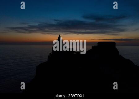 Luftaufnahme mit einer Drohne, die über die Kirche San Pietro in Portovenere fliegt, von der Landseite aus gesehen mit einer Silhouette, die gegen das s geschlickt wurde Stockfoto