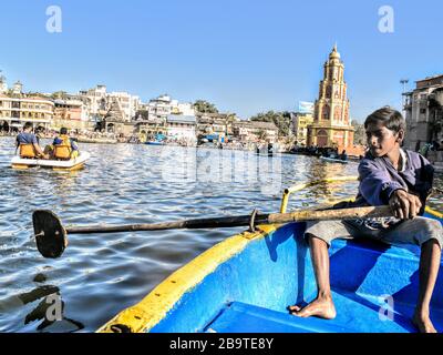 Ein überlieferter Junge, der Touristen auf einem Boot in Nashik, Indien rudert Stockfoto