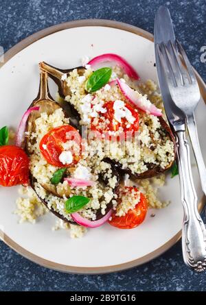 Gebackene Auberginen gefüllt mit Couscous, Tomaten, Feta- und Basilikumblättern, Draufsicht. Stockfoto