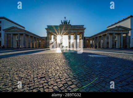 23.03.2020, das Brandenburger Ziel in Berlin an einem späten Frühlingssaftstag in der tiefen Sonne. Die Sonne scheint durch die Prophylaxe und erzeugt eine besondere Licht- und Schattenstimmung. Wegen der Koronakrise sind in Berlin nur wenige Menschen auf den Straßen und Plätzen. Weltweite Verwendung Stockfoto