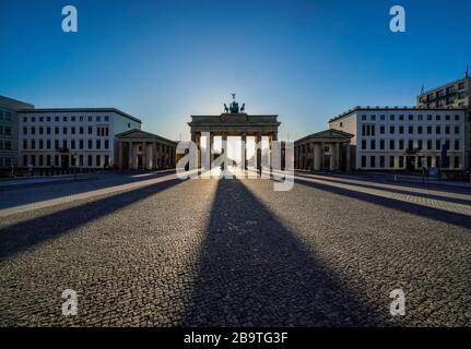 23.03.2020, das Brandenburger Ziel in Berlin an einem späten Frühlingssaftstag in der tiefen Sonne. Die Sonne scheint durch die Prophylaxe und erzeugt eine besondere Licht- und Schattenstimmung. Wegen der Koronakrise sind in Berlin nur wenige Menschen auf den Straßen und Plätzen. Weltweite Verwendung Stockfoto