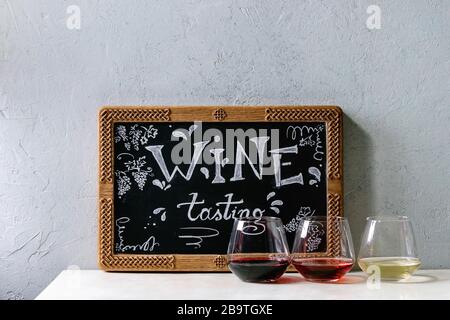 Vielzahl von Wein. Rotwein, Rosé und Weißwein in Old Fashion Brillen und dekorative Kreidetafel mit handschriftlichen Chalk Schriftzug Weinprobe auf weißem Marb Stockfoto