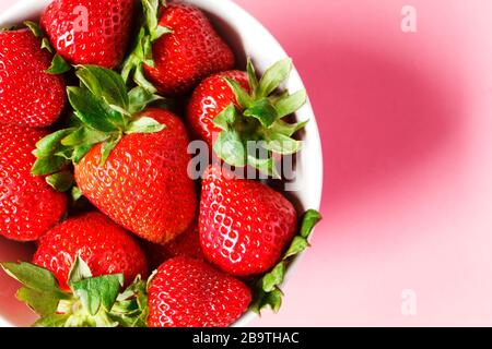 Erdbeeren in Schüsseln auf pinkfarbenem Hintergrund, Draufsicht, Kopierbereich Stockfoto