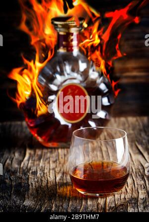 Glas Cognac und eine Flasche Cognac auf Holzgrund Stockfoto