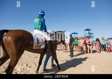 Ein weiblicher, montierter Jockey kehrt nach einem Rennen während der jährlichen Horseraces im August am Strand von Sanlucar de Barrameda, Cadiz, Spanien, ins Gehäuse zurück Stockfoto