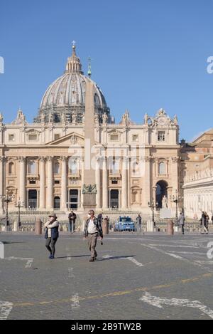 ROM, ITALIEN - 12. März 2020: Touristen, die Gesichtsmasken tragen, gehen um einen leeren Petersplatz, Vatikan, Italien. Nach der Coronavirus-Pandemie Stockfoto