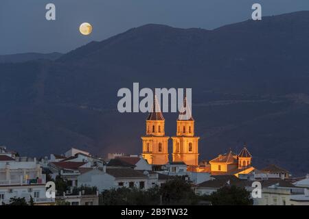 Der aufsteigende Mond in der Endphase einer Mondfinsternis und die beiden Glockentürme der Kirche in Órgiva, Granada, Andalusien, Spanien. August 2017. Stockfoto