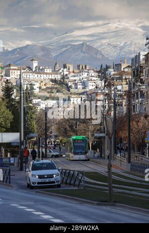 Avenida de la Constitución, weiße Gebäude des Viertels Albaicin auf dem Hügel, schneebedeckte Berge der Sierra Nevada dahinter. Granada, Spanien Stockfoto