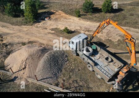 Betonringe für den Bau von Brunnen und Abwasserkanälen in der Draufsicht entladen Stockfoto