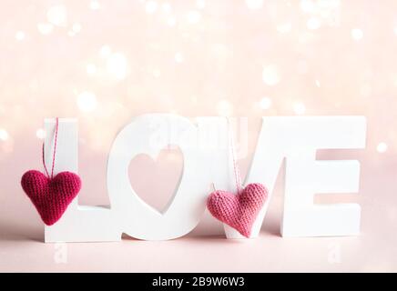 Wort Liebe und rosafarbene Herzen im rosafarbenen Hintergrund Stockfoto
