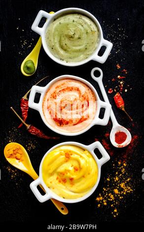 Vegane Mandeln Mayonnaise mit Wasabi, Chili und Kurkuma in Schale auf schwarzem Hintergrund. Milch-, Ei- und sojafrei. Draufsicht. Stockfoto