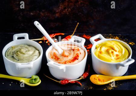 Vegane Mandeln Mayonnaise mit Wasabi, Chili und Kurkuma in Schale auf schwarzem Hintergrund. Milch-, Ei- und sojafrei Stockfoto