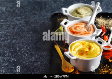 Vegane Mandeln Mayonnaise mit Wasabi, Chili und Kurkuma in Schale auf schwarzem Hintergrund. Milch-, Ei- und sojafrei. Stockfoto