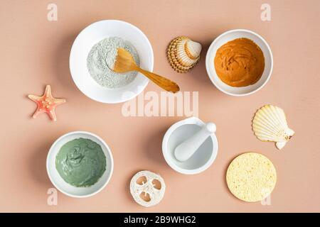 Gesichtsmasken aus Ton auf Pfirsichfarbenhintergrund mit Muscheln. SPA natürliche organische Kosmetik, sommerliches Gesichtshautpflegekonzept. Draufsicht, flacher Lay. Stockfoto