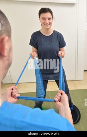 Ein junger männlicher Physiotherapeut hilft einem Teenager-Mädchen bei Dehnübungen Stockfoto