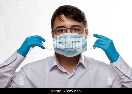 Corona Virus Kovid 19: Nahaufnahme mit dem Gesicht eines jungen Arztes mit Brille und tragen einer medizinischen oder chirurgischen Maske Stockfoto