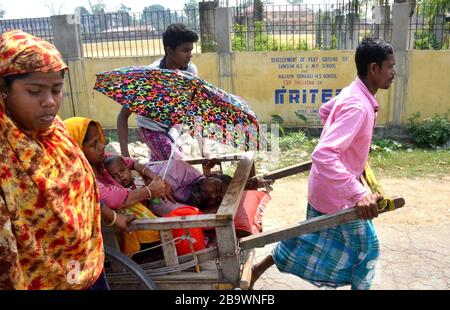 Nagaon/Indien - Personen, die einen Patienten in Handwagen tragen, weil während der von der Regierung Indiens angerufenen Sperre keine Fahrzeuge verfügbar sind. Stockfoto