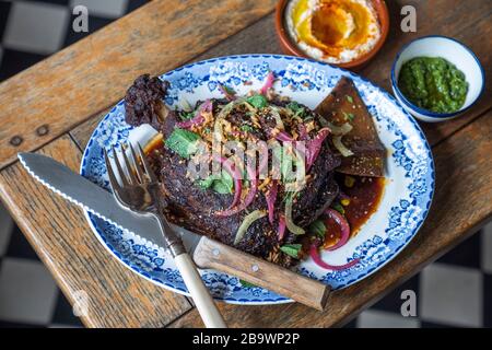 Geräucherte Lamb-Schulter mit eingelegten Zwiebeln, Granatapfel und knusprigen Schalotten Stockfoto