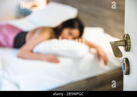 Entschärfte junge müde Frau in Quarantäne wegen Coronavirus, legte sich im Bett und fühlte sich tagsüber eingeschlafen Stockfoto
