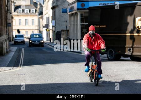 Ein Mann, der eine Gesichtsschutzmaske trägt, fährt mit seinem Fahrrad durch Bath, nachdem die Regierung strenge neue Einschränkungen angekündigt hatte, um Coronavirus zu versuchen und einzudämmen. Stockfoto