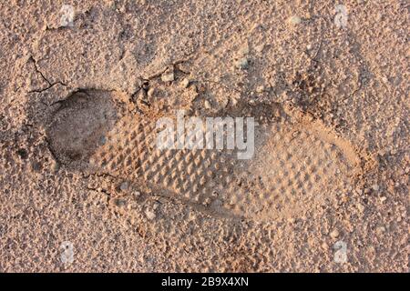 Imprint von Schuhen auf Sand. Einsamer menschlicher Fußabdruck auf einer sandigen Oberfläche Stockfoto