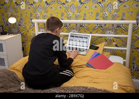 Junge arbeitet zu Hause an seiner Schularbeit, da die Schulen geschlossen sind. Stockfoto