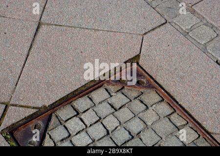 eisenmanloch mit Pflastersteinen und Boden aus Granitplatten in der Stadt, Gehweg mit rostigem Manloch in der Nähe von Pflastersteinen Stockfoto