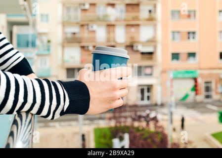 Nahaufnahme eines jungen kaukasischen Mannes mit legeren Kleidungsstücken, Kaffee auf dem Balkon seines Hauses oder eines Hotels Stockfoto