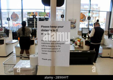 Ein Zeichen in Sainsbury's weist Kunden an, die soziale Distanzierung während des Ausbruchs des Corona-Virus in london england UK zu respektieren Stockfoto