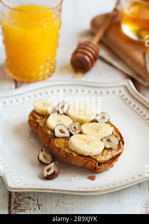 Toast mit Bananen, Erdnussbutter, Nüssen und Honig Stockfoto