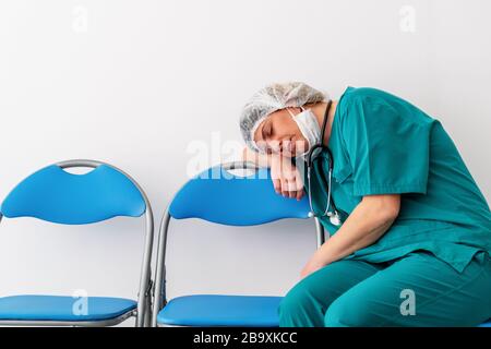 Frau Doktor sitzt und schlief ein, wegen der Sorge, Frustration, Müdigkeit und Erschöpfung der globalen Infektion Kovid 19 Stockfoto