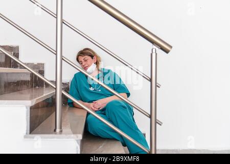 Frau Doktor sitzt und schlief ein, wegen der Sorge, Frustration, Müdigkeit und Erschöpfung der globalen Infektion Kovid 19 Stockfoto