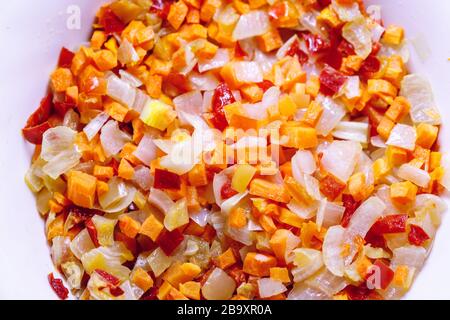 Gedämpftes Gemüse auf einem Teller. Zwiebeln, süße rote Paprika, Karotten, Pflanzenöl. Ingwersuppe grillen. Stockfoto