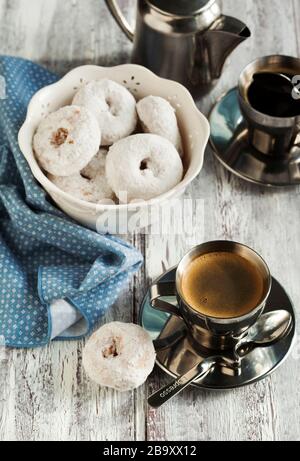 Süße Donuts mit Puderzucker und zwei Tassen Kaffee Stockfoto