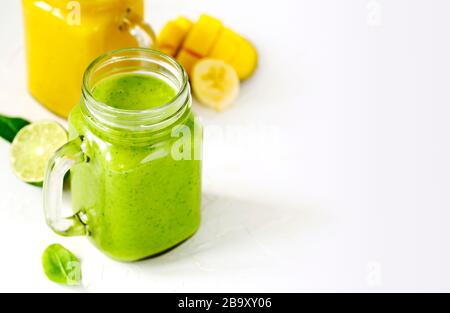 Grüner Spinat Avocado Smoothie und Banana Mango Smoothie in Maurer-Gläsern. Gesundes veganes Essen. Stockfoto