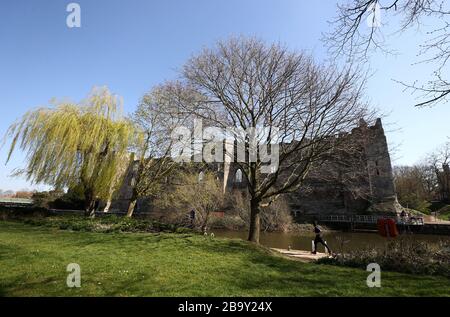 Ein Mann joggt an den Ufern des Kanals unter Newark Castle im Riverside Park, Newark-on-Trent, nachdem Premierminister Boris Johnson Großbritannien in Sperrstellung versetzt hat, um die Ausbreitung des Coronavirus einzudämmen. Stockfoto