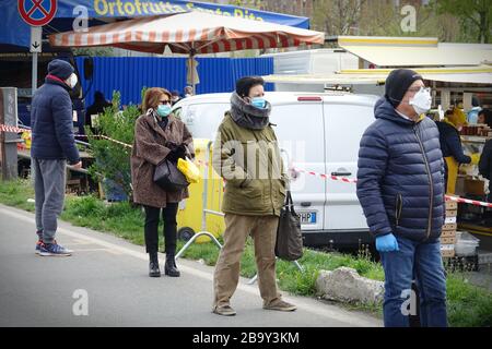 Leute, die Schlange stehen, um einzukaufen, warten auf den Markt im Freien. Soziale Distanzierung. Vorbeugende Maßnahmen. Turin, Italien - März 2020 Stockfoto