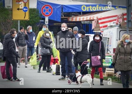 Leute, die Schlange stehen, um einzukaufen, warten auf den Markt im Freien. Soziale Distanzierung. Vorbeugende Maßnahmen. Turin, Italien - März 2020 Stockfoto