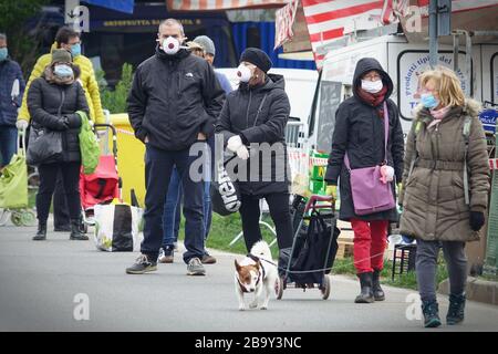 Leute, die Schlange stehen, um einzukaufen, warten auf den Markt im Freien. Soziale Distanzierung. Vorbeugende Maßnahmen. Turin, Italien - März 2020 Stockfoto