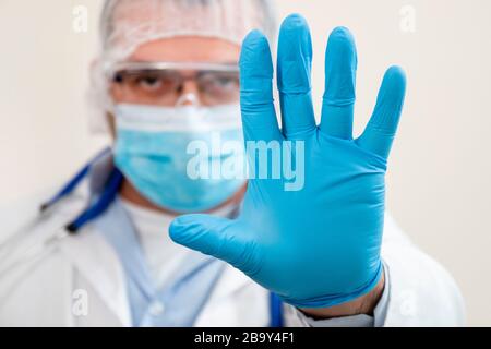 kaukasischer Arzt zeigt Handstoppzeichen mit Schutzausrüstung. Stockfoto