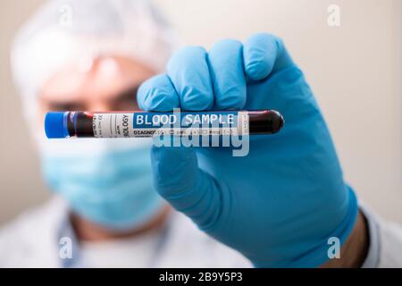 Ansicht eines Arztes, der eine fiktive, mit Virus infizierte Reagenzglasblutprobe hält. Stockfoto