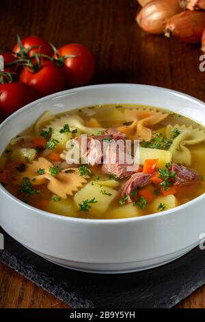 Suppe mit geräuchertem Fleisch, Gemüse und Pasta in einer weißen Schüssel Stockfoto