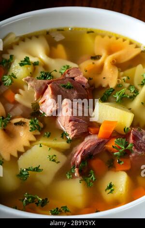 Suppe mit geräuchertem Fleisch, Gemüse und Pasta in einer weißen Schüssel Stockfoto