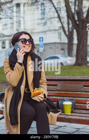 Junge Schönheit Business woman Essen fast food und Arbeiten am Telefon während der Sitzung im City Bank Stockfoto