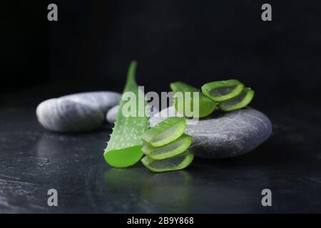 Frisches Aloe Vera Gebläse mit Spa Steinen auf dunklem Hintergrund Stockfoto