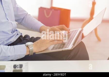 Ein Geschäftsmann mit einer Nahaufnahme in einem blauen Hemd, Tastatur, Text auf einem modernen Notebook-Computer an einem Schreibtisch im Haus Männer arbeiten online über Banken auf Netboo Stockfoto
