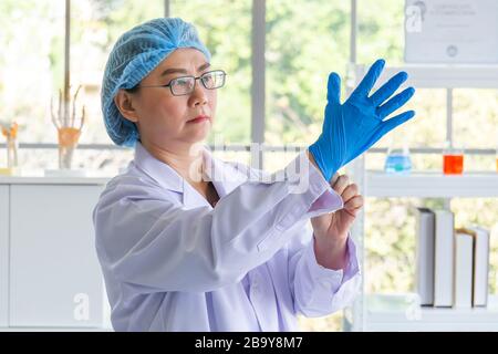 Asiatische Wissenschaftlerinnen tragen blaue Gummihandschuhe Stockfoto